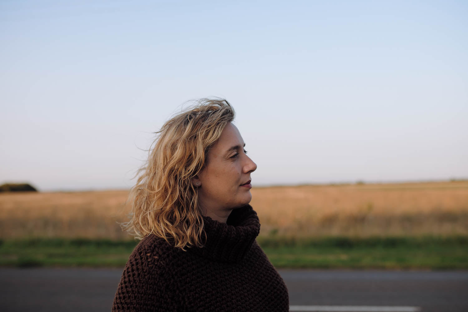 woman stands in a field wearing a crochet jumper (chunky monkey sweater)