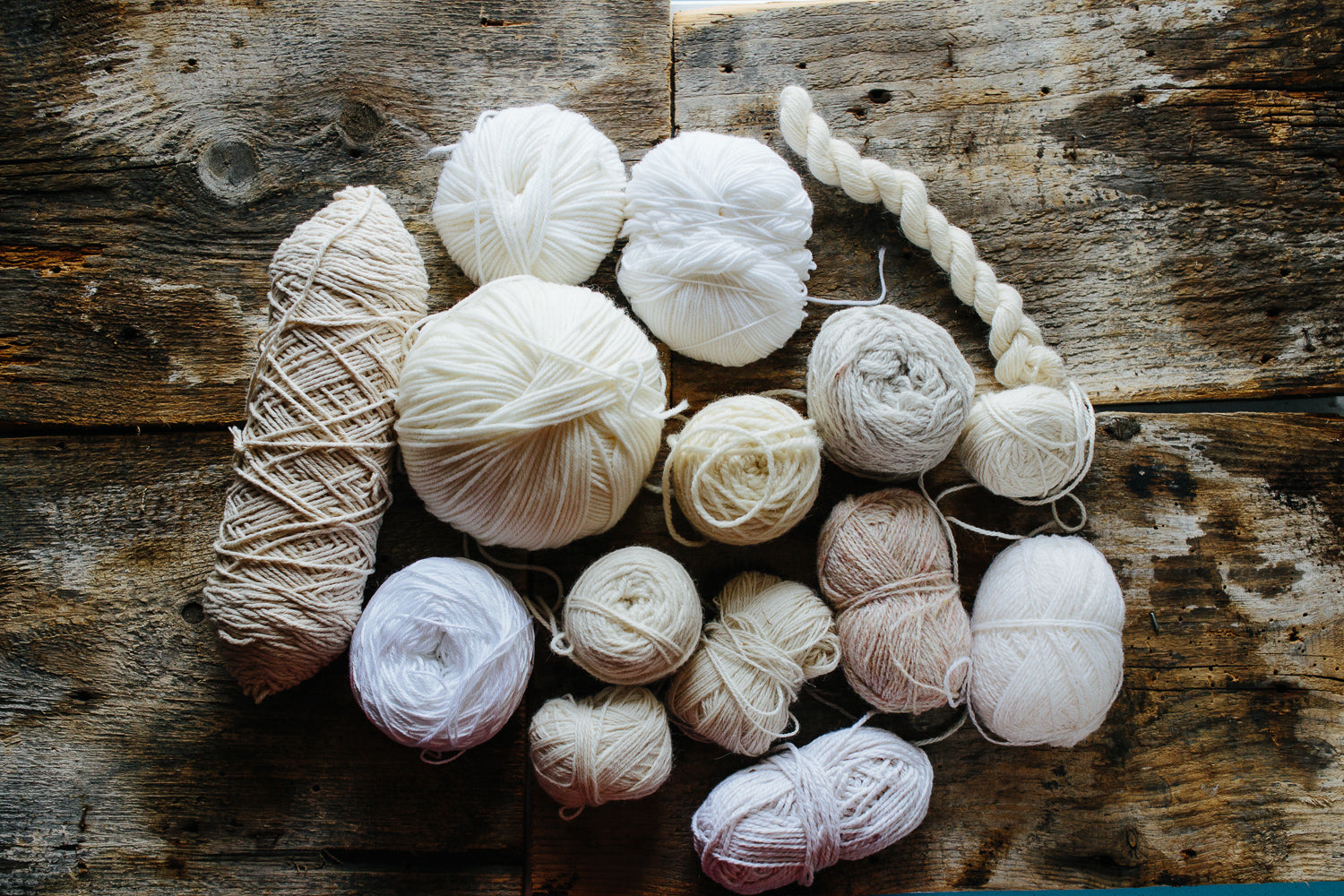 selection of cream and white yarns on a wood background