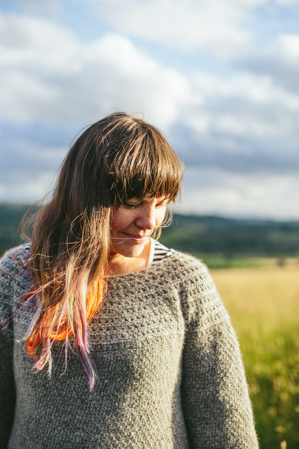woman in a field wearing grey crochet jumper (lindridge sweater)